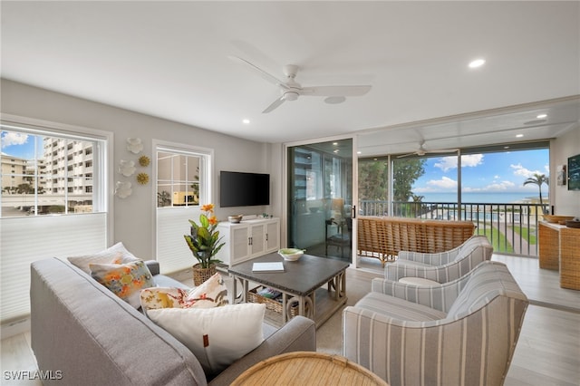 living room with a healthy amount of sunlight, ceiling fan, and light hardwood / wood-style flooring