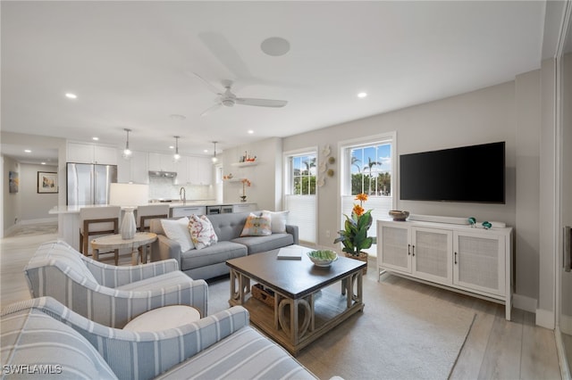 living room with sink, ceiling fan, and light hardwood / wood-style flooring