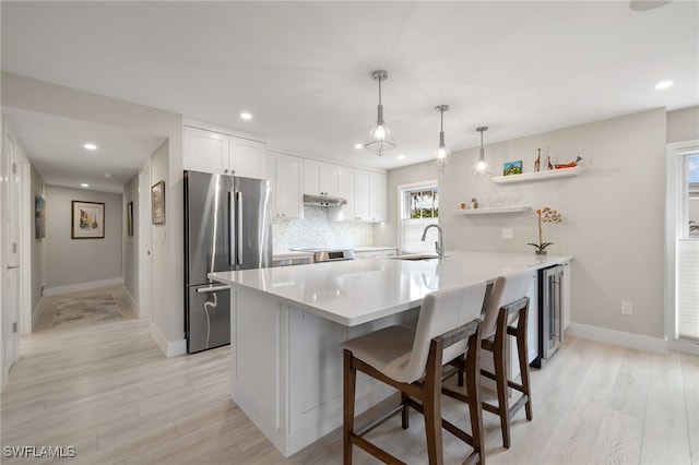 kitchen featuring stainless steel refrigerator, white cabinetry, sink, backsplash, and kitchen peninsula