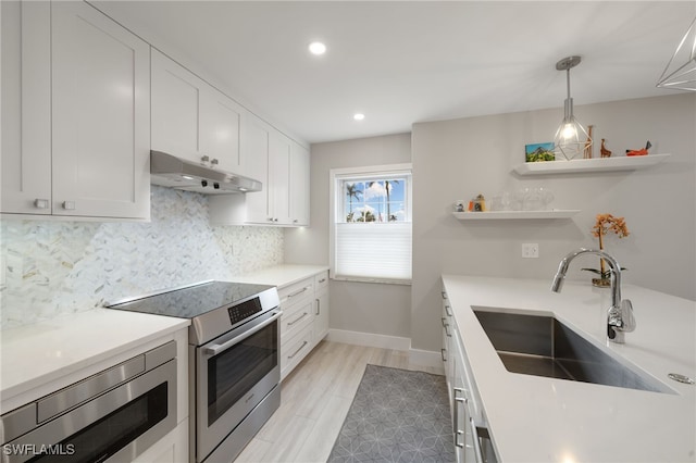 kitchen with sink, hanging light fixtures, white cabinets, stainless steel appliances, and backsplash