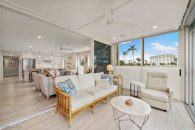 living room featuring ceiling fan, floor to ceiling windows, sink, and light hardwood / wood-style flooring