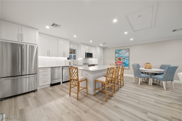 kitchen with sink, a breakfast bar area, appliances with stainless steel finishes, white cabinetry, and a kitchen island