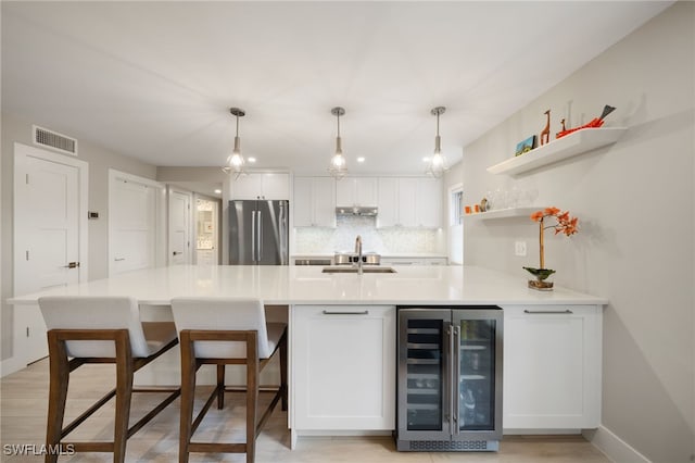 kitchen featuring sink, tasteful backsplash, stainless steel fridge, beverage cooler, and white cabinets