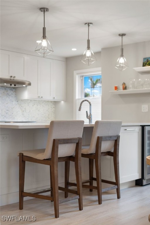 kitchen with white cabinetry, backsplash, a kitchen breakfast bar, and beverage cooler