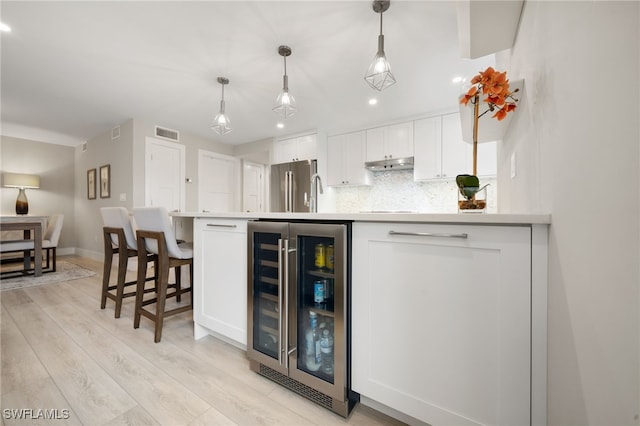 bar with stainless steel refrigerator, wine cooler, decorative backsplash, and white cabinets