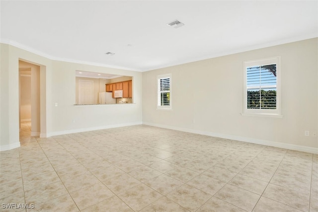 empty room featuring crown molding, a healthy amount of sunlight, and light tile patterned floors