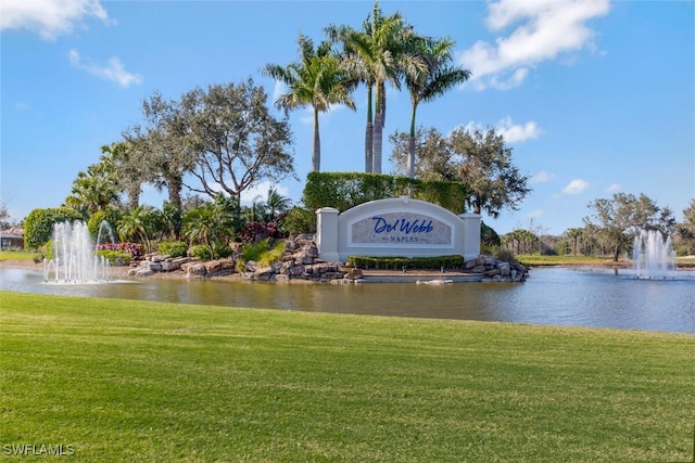 community sign featuring a yard and a water view