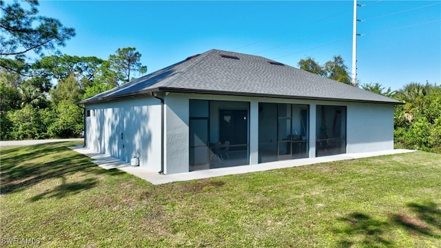 rear view of house featuring a lawn and a sunroom