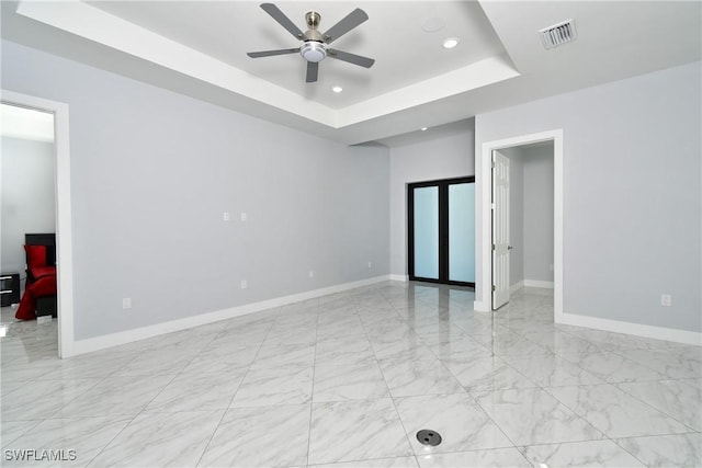 unfurnished room featuring a raised ceiling and ceiling fan