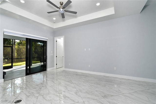 spare room with ceiling fan and a tray ceiling