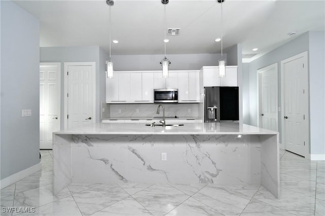 kitchen with appliances with stainless steel finishes, decorative light fixtures, a center island with sink, and sink