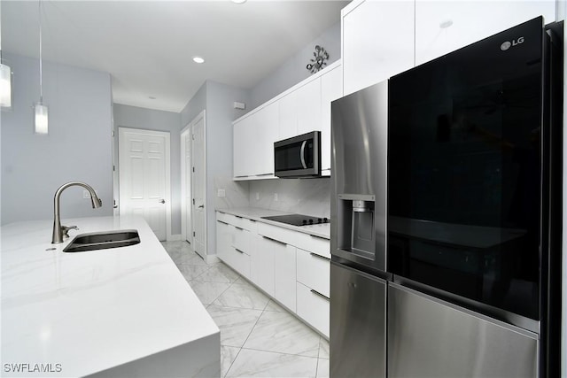 kitchen featuring light stone countertops, decorative light fixtures, stainless steel appliances, white cabinets, and sink