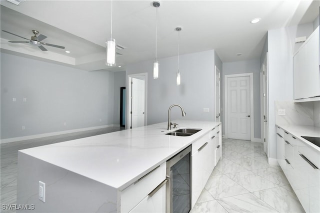 kitchen featuring sink, decorative light fixtures, white cabinetry, ceiling fan, and a spacious island