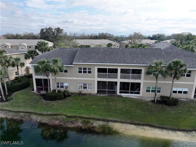 rear view of house with a lawn and a water view