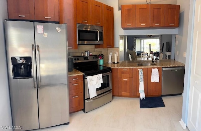 kitchen featuring appliances with stainless steel finishes, tasteful backsplash, light stone counters, and sink