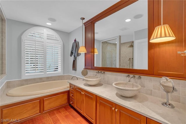 bathroom with decorative backsplash, wood-type flooring, vanity, and shower with separate bathtub