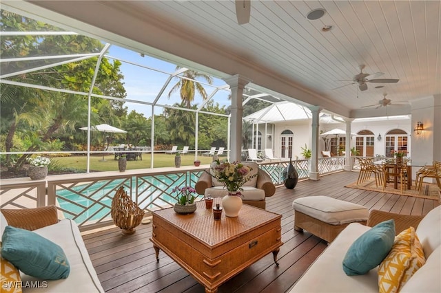 wooden terrace featuring ceiling fan, a yard, glass enclosure, and an outdoor hangout area