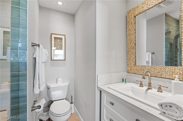 bathroom featuring a shower with door, vanity, and toilet