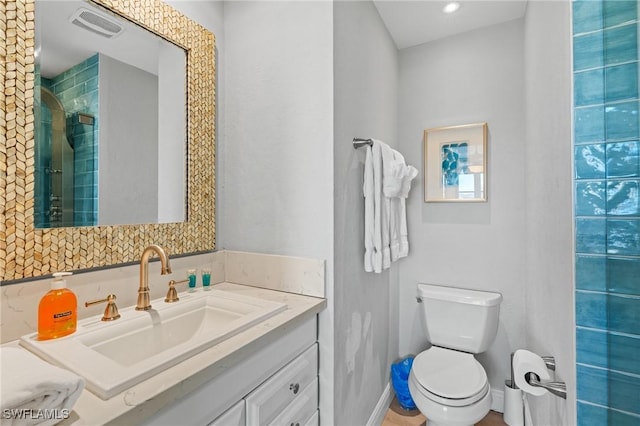 full bath with visible vents, baseboards, toilet, tiled shower, and vanity