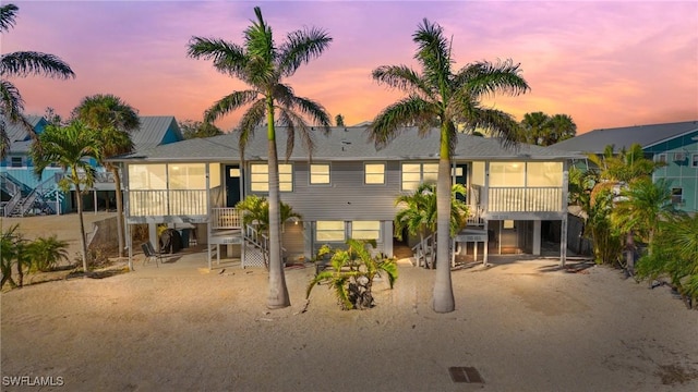 back of house at dusk featuring a carport and a sunroom