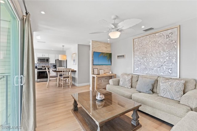 living room featuring ceiling fan and light hardwood / wood-style flooring