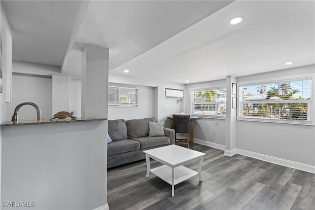 living room with plenty of natural light, dark hardwood / wood-style floors, an AC wall unit, and sink