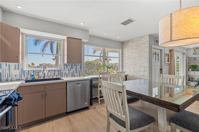 kitchen featuring visible vents, a sink, backsplash, light wood-style floors, and appliances with stainless steel finishes