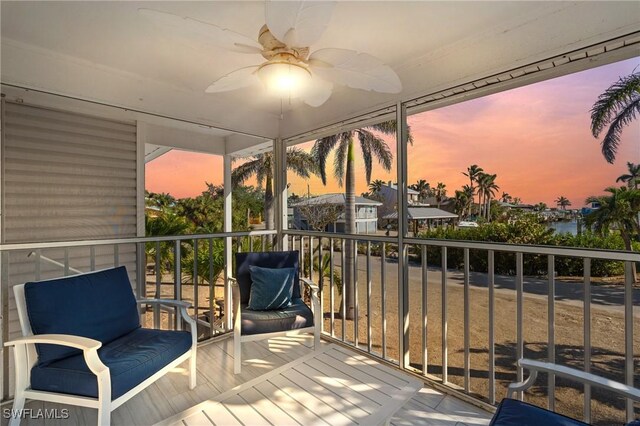 balcony at dusk featuring ceiling fan