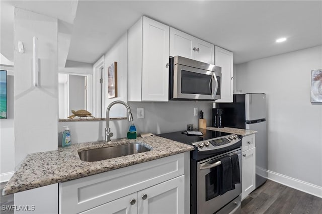 kitchen with light stone countertops, sink, white cabinetry, and stainless steel appliances