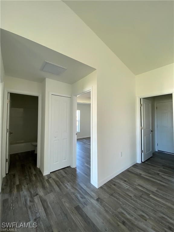 unfurnished room with dark wood-type flooring and lofted ceiling