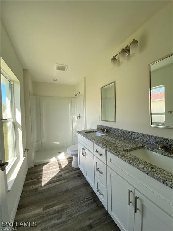 bathroom featuring walk in shower, wood-type flooring, vanity, and toilet