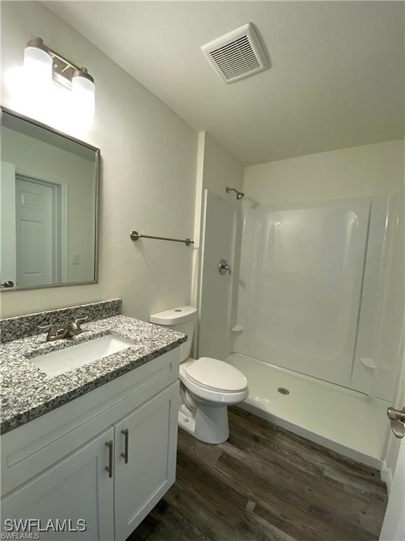 bathroom featuring walk in shower, wood-type flooring, toilet, and vanity