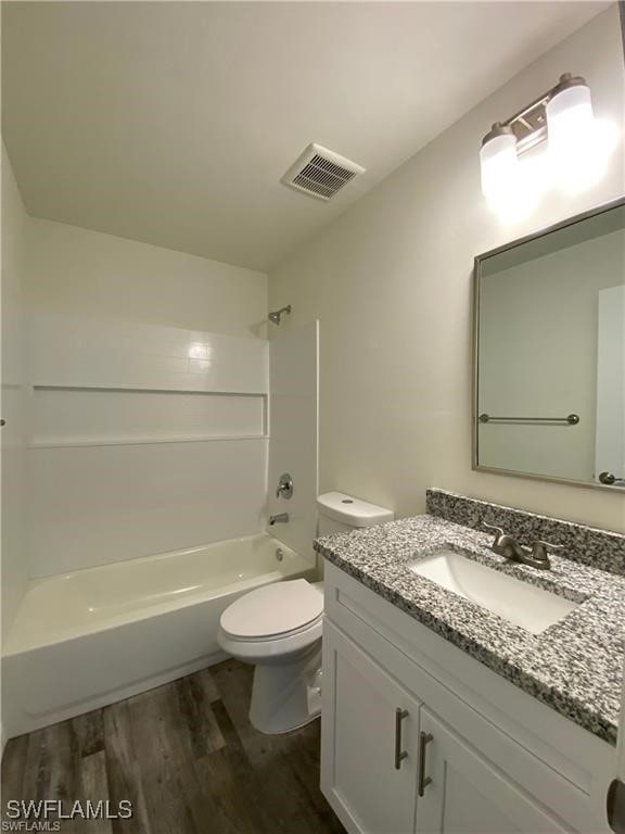 full bathroom with  shower combination, toilet, hardwood / wood-style floors, and vanity