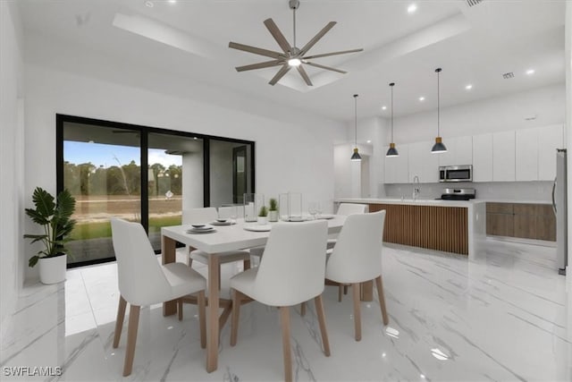 dining room with ceiling fan, a tray ceiling, and sink