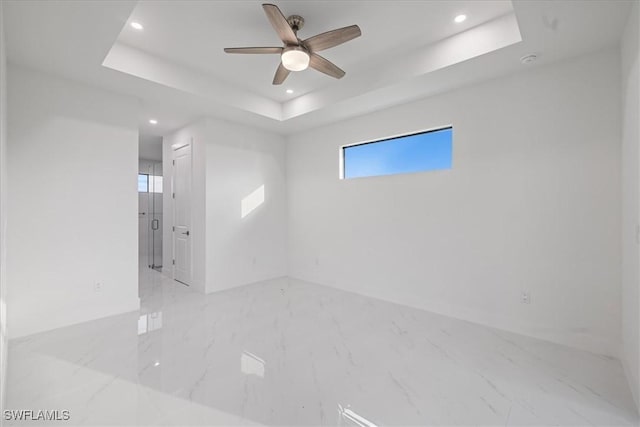 empty room featuring ceiling fan and a raised ceiling