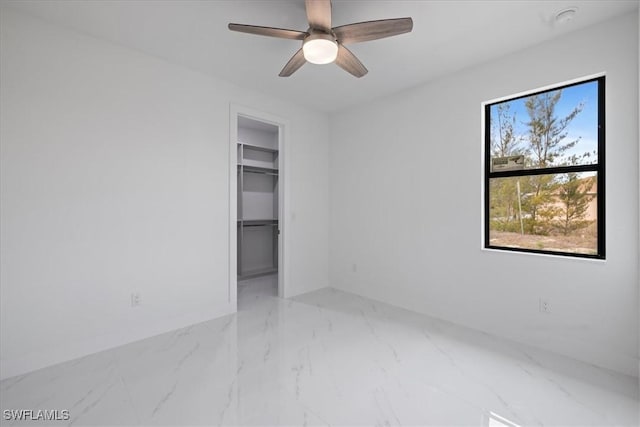 unfurnished bedroom with ceiling fan, a spacious closet, and a closet