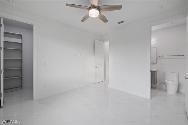 unfurnished bedroom featuring ceiling fan, a walk in closet, ensuite bath, and a closet