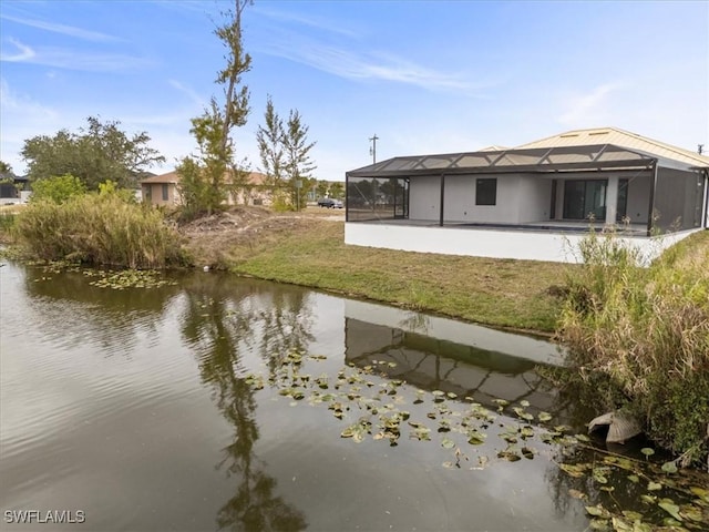 rear view of house featuring a yard, a patio area, a water view, and glass enclosure