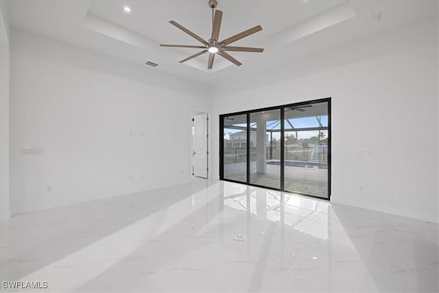 spare room with a towering ceiling, a raised ceiling, and ceiling fan