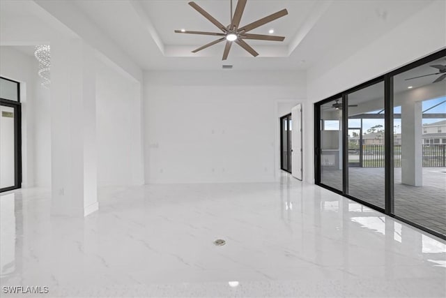 spare room featuring a raised ceiling and ceiling fan