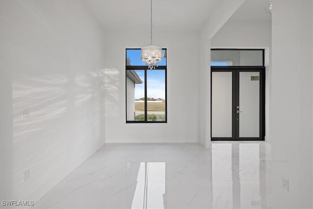 empty room featuring an inviting chandelier and french doors