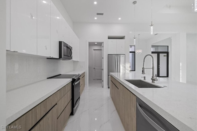 kitchen with sink, white cabinetry, hanging light fixtures, backsplash, and stainless steel appliances