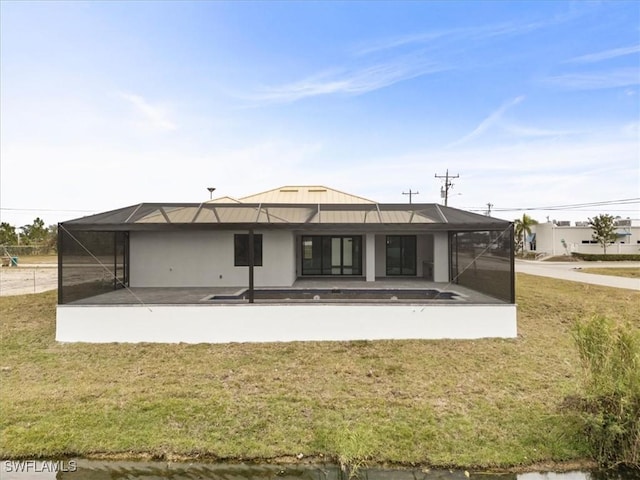 rear view of house featuring a patio area, glass enclosure, and a lawn