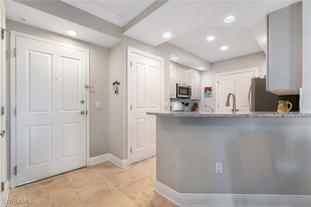 kitchen featuring crown molding, appliances with stainless steel finishes, tasteful backsplash, white cabinetry, and kitchen peninsula