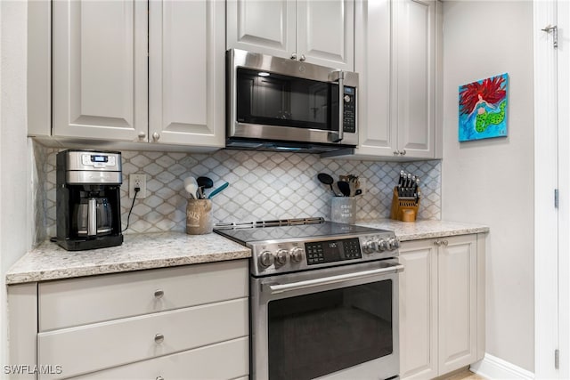 kitchen featuring backsplash, light stone counters, and stainless steel appliances