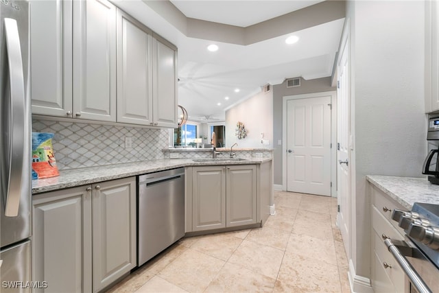 kitchen with decorative backsplash, light stone countertops, gray cabinetry, stainless steel appliances, and sink