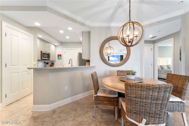 dining area with a chandelier, ornamental molding, and sink