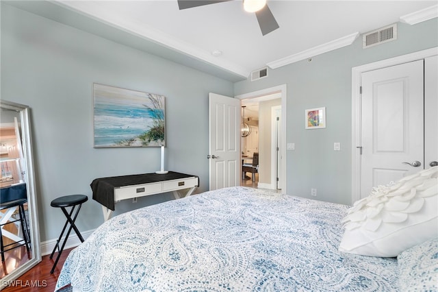 bedroom with ceiling fan, ornamental molding, dark wood-type flooring, and a closet