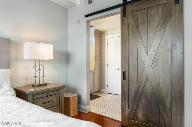 bedroom with a barn door and dark hardwood / wood-style flooring