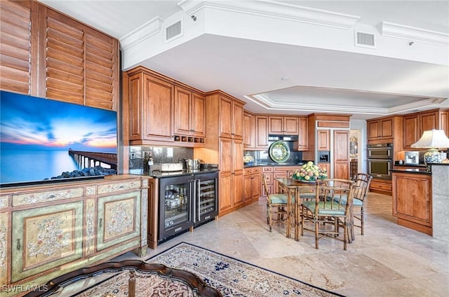 kitchen featuring a raised ceiling, wine cooler, crown molding, stainless steel double oven, and backsplash